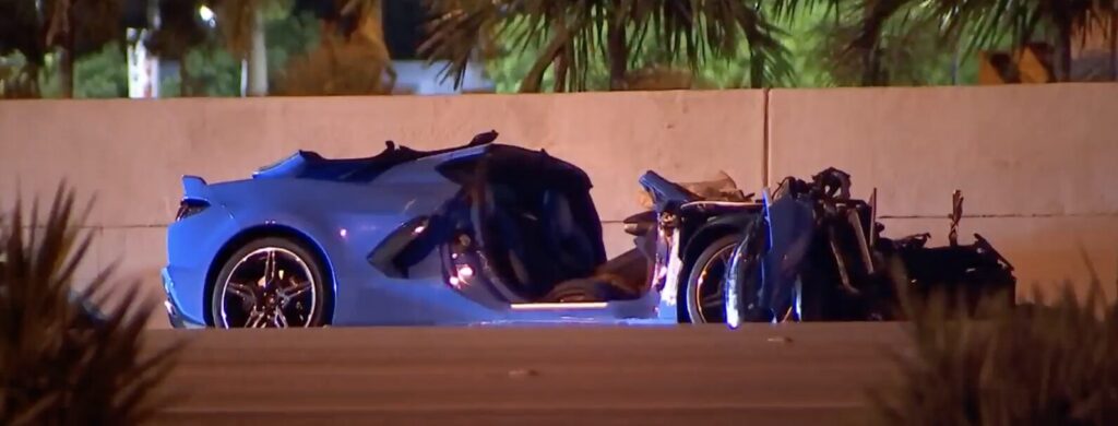 A blue Corvette with severe front-end damage crashed against a concrete barrier on the Dolphin Expressway in Doral, Florida, at night.